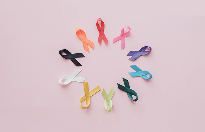 Cancer awareness ribbons placed on a pink background.