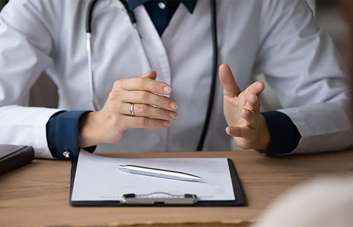 A doctor with a clipboard speaking with a patient.