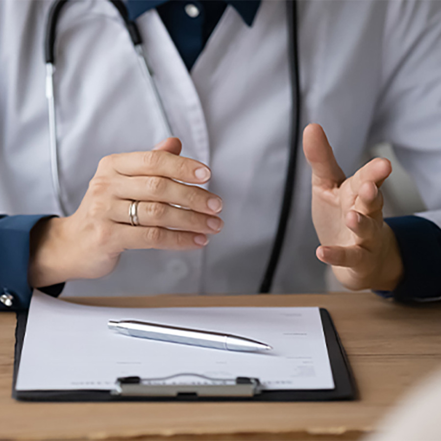 A doctor with a clipboard speaking with a patient.