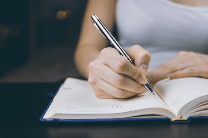 Right-handed person writing in journal.