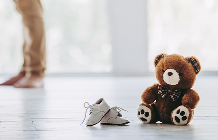 Expecting couple with teddy bear and baby shoes ready.
