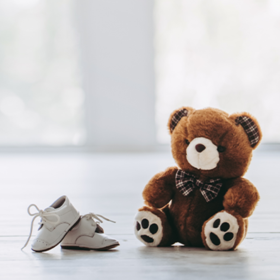 Expecting couple with teddy bear and baby shoes ready.