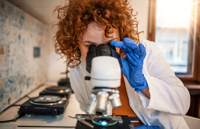 Redheaded woman looking through a microscope.