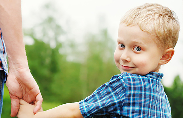Little boy holding hand with father.