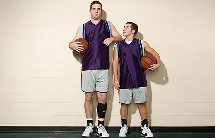 Tall and short basketball players standing side-by-side.