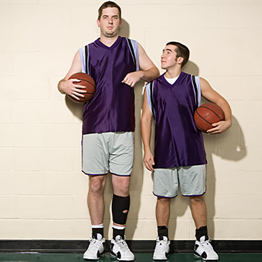 Tall and short basketball players standing side-by-side.