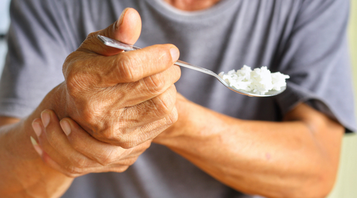 Elderly hand holding spoon.