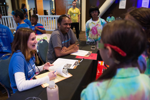 Two adult volunteers sit at a table smiling while checking in museum visitors.