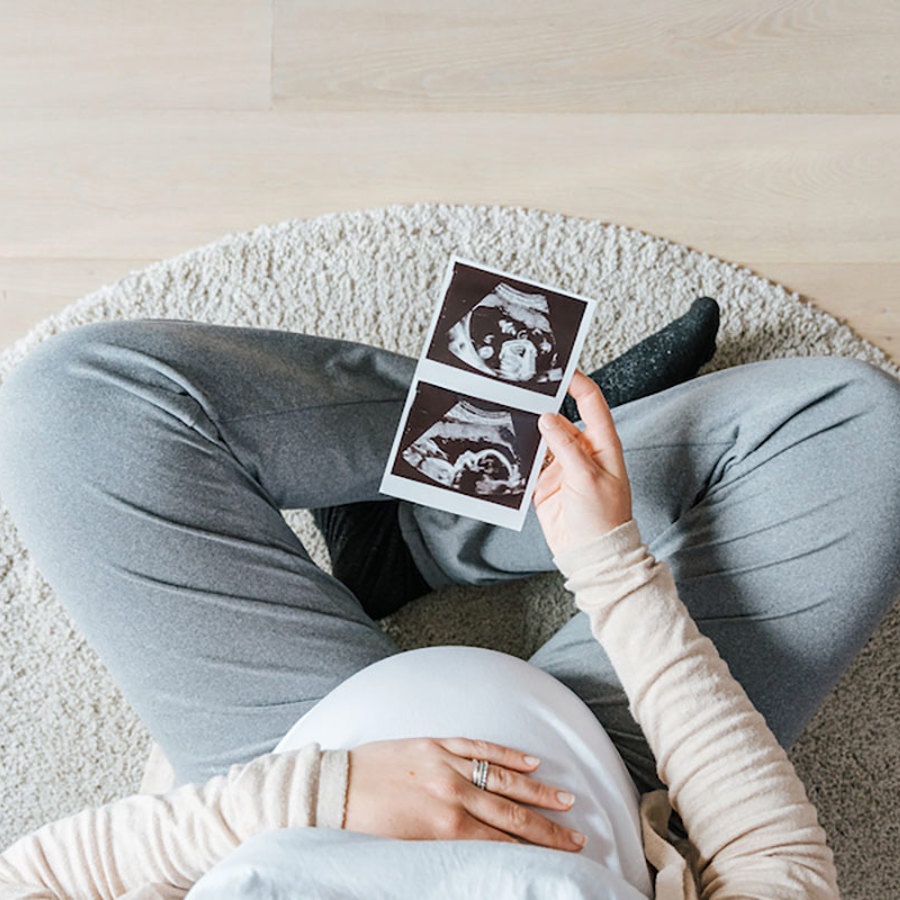 Pregnant woman holding a sonogram.