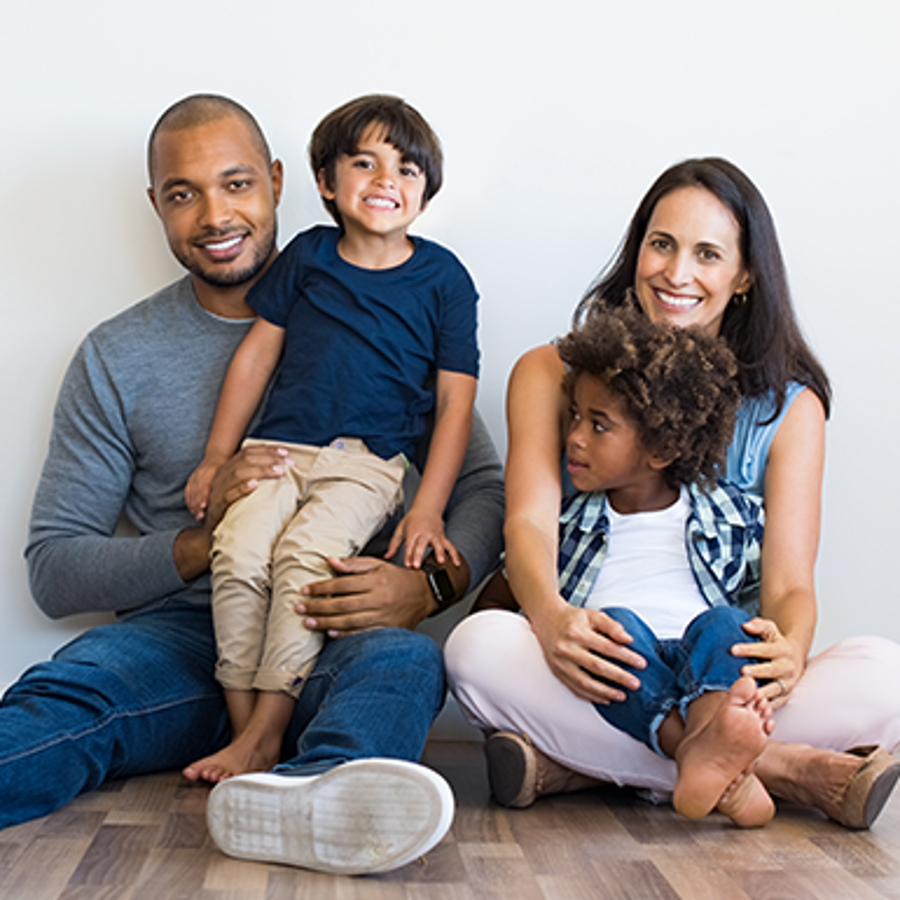 Happy multi-ethnic family sitting together on floor.