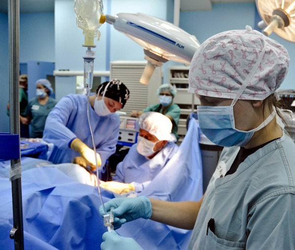 Three medical professionals working in an operating room.