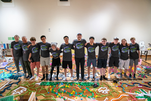 Reactica team members stand together in front of a colorful domino and chain-reaction setup after the 2025 Tech Topple at The Tech Interactive.