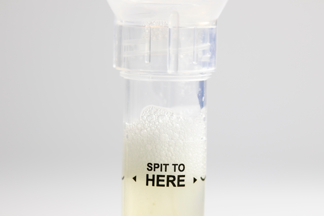 Sample collection tube with label “SPIT TO HERE”.