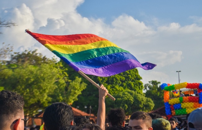 People at a pride festival waving a rainbow flag.